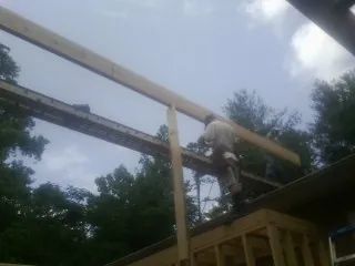 Carpenter setting a ridge beam over a new addition frame in Corolla