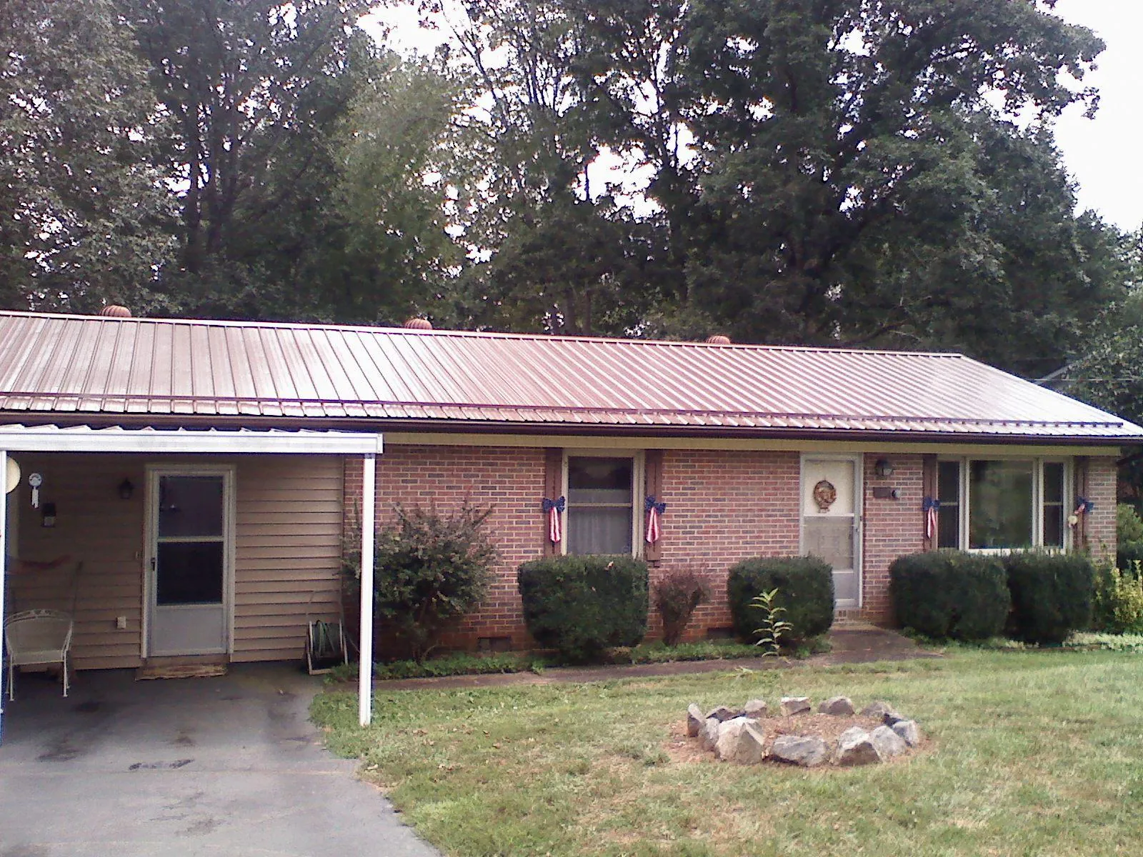 Bronze metal roof and carport on a brick ranch home — Roof Repair work by our crew in Corolla