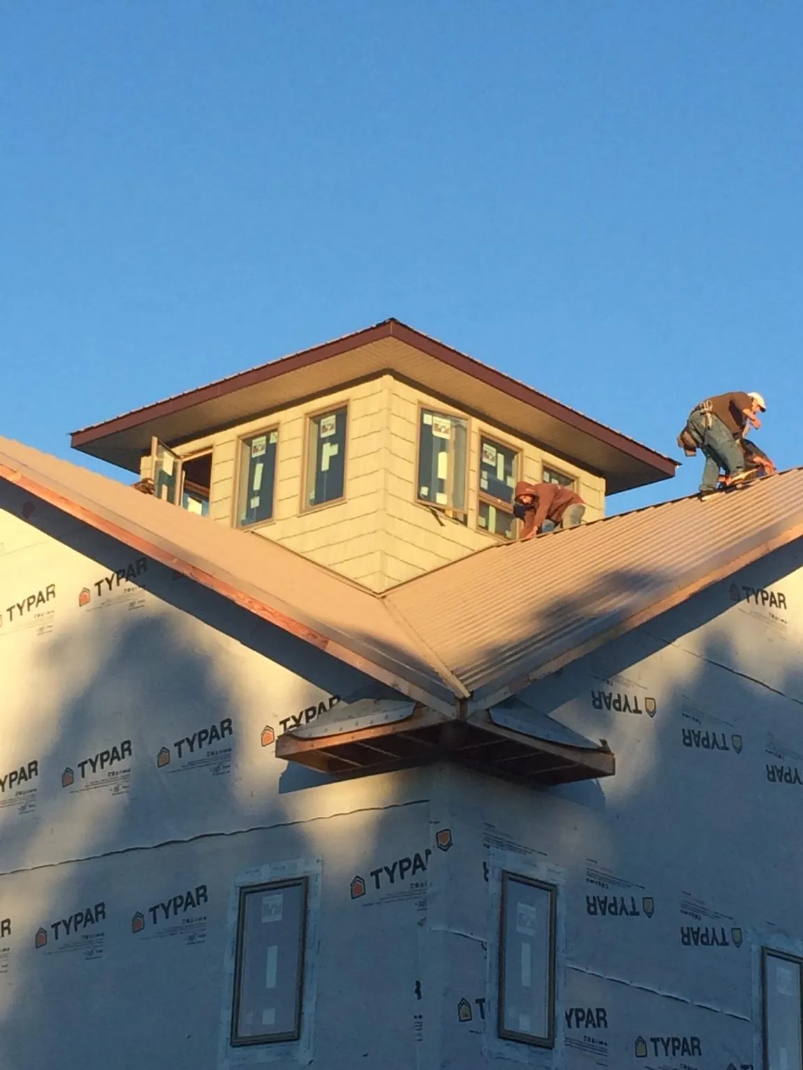 Roofers working around a rooftop cupola on a new metal roof at sunset — Roof Waterproofing in Corolla by Roofing Brothers